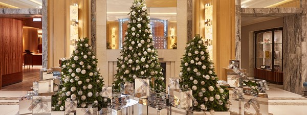 Three christmas trees decorated in gold and silver in hotel lobby