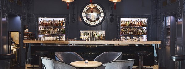 Four deep blue lounge chairs around a table in front of the bar with blue interior