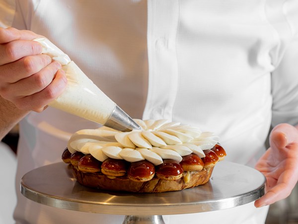 Chef in white shirt piping the vanilla flower patisserie by Cedric Grolet